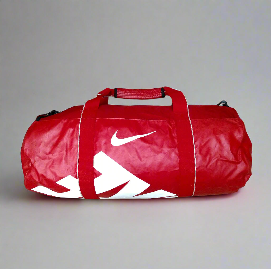 Red duffel bag with a white logo on a beige tiled floor.