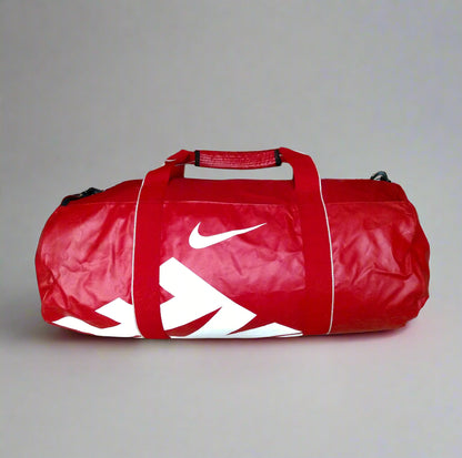 Red duffel bag with a white logo on a beige tiled floor.