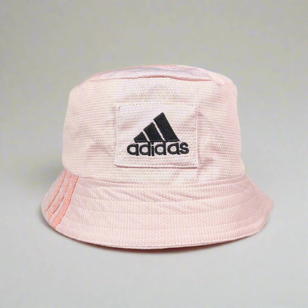 Pink bucket hat with Adidas logo held against a gray background