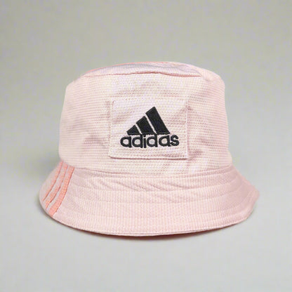 Pink bucket hat with Adidas logo held against a gray background